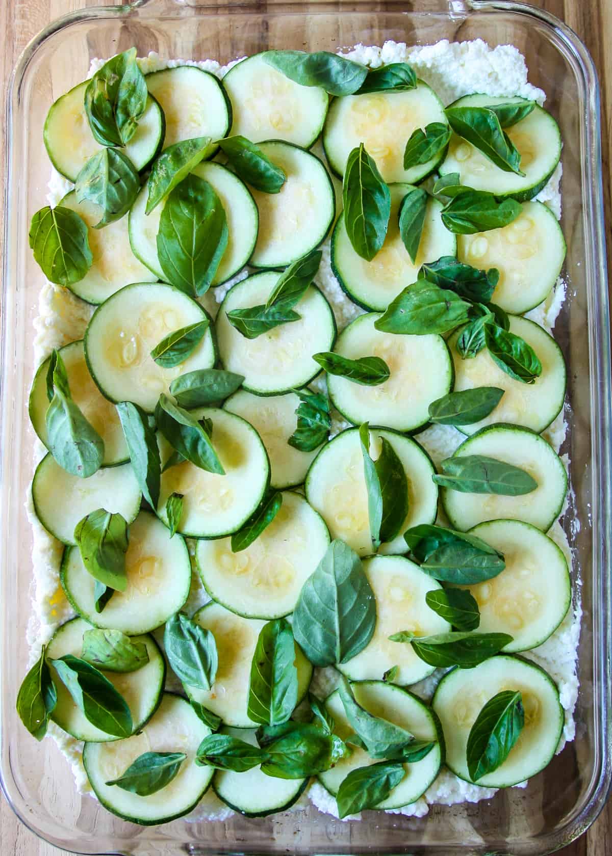 Zucchini slices layered over the ricotta cheese and sprinkled with basil leaves.