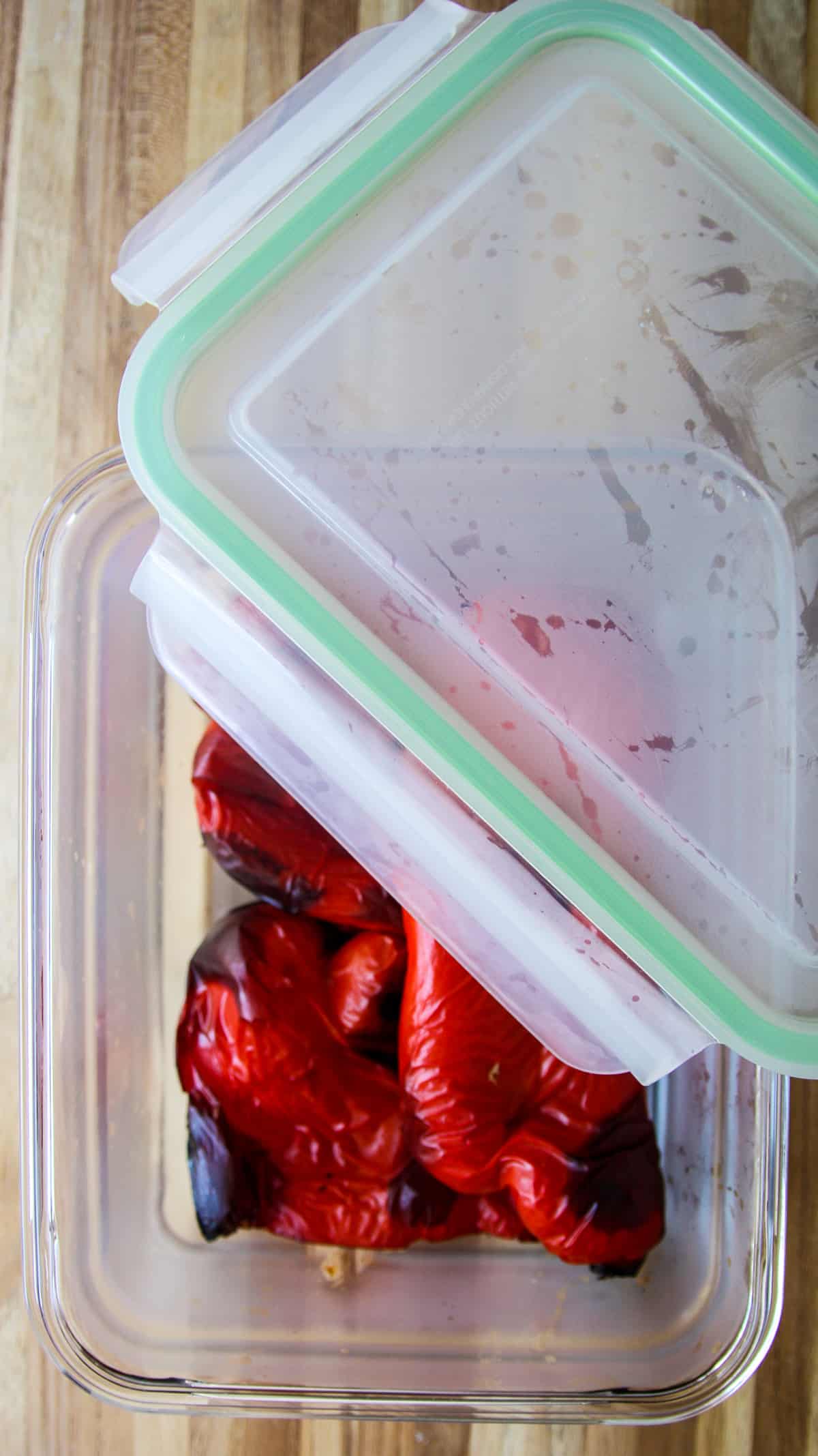 The hot roasted red peppers steaming in a glass dish with a lid.