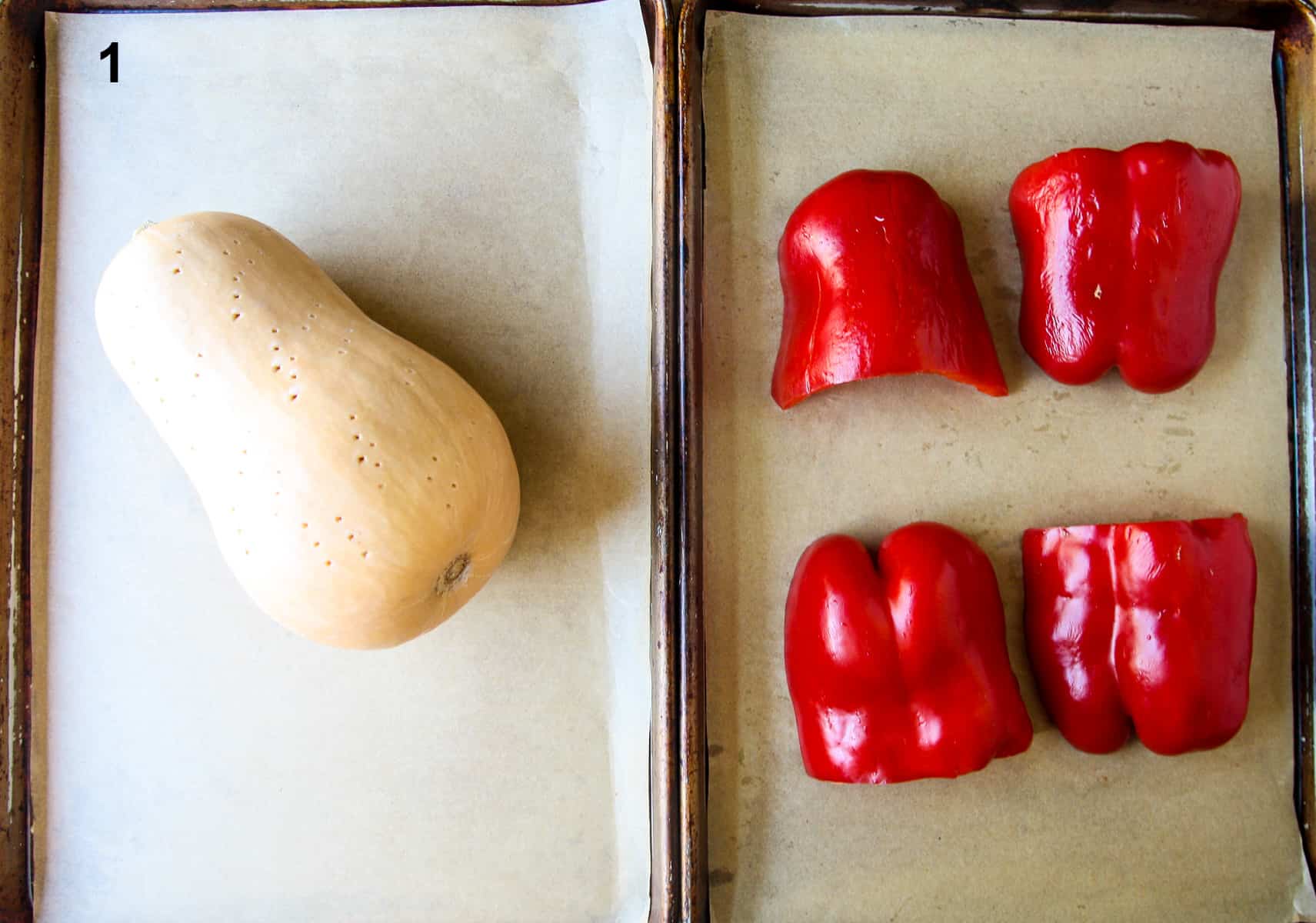 Whole butternut squash and halved red bell peppers on baking sheets ready to be roasted. 