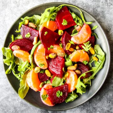 Beet and orange salad on a black plate.