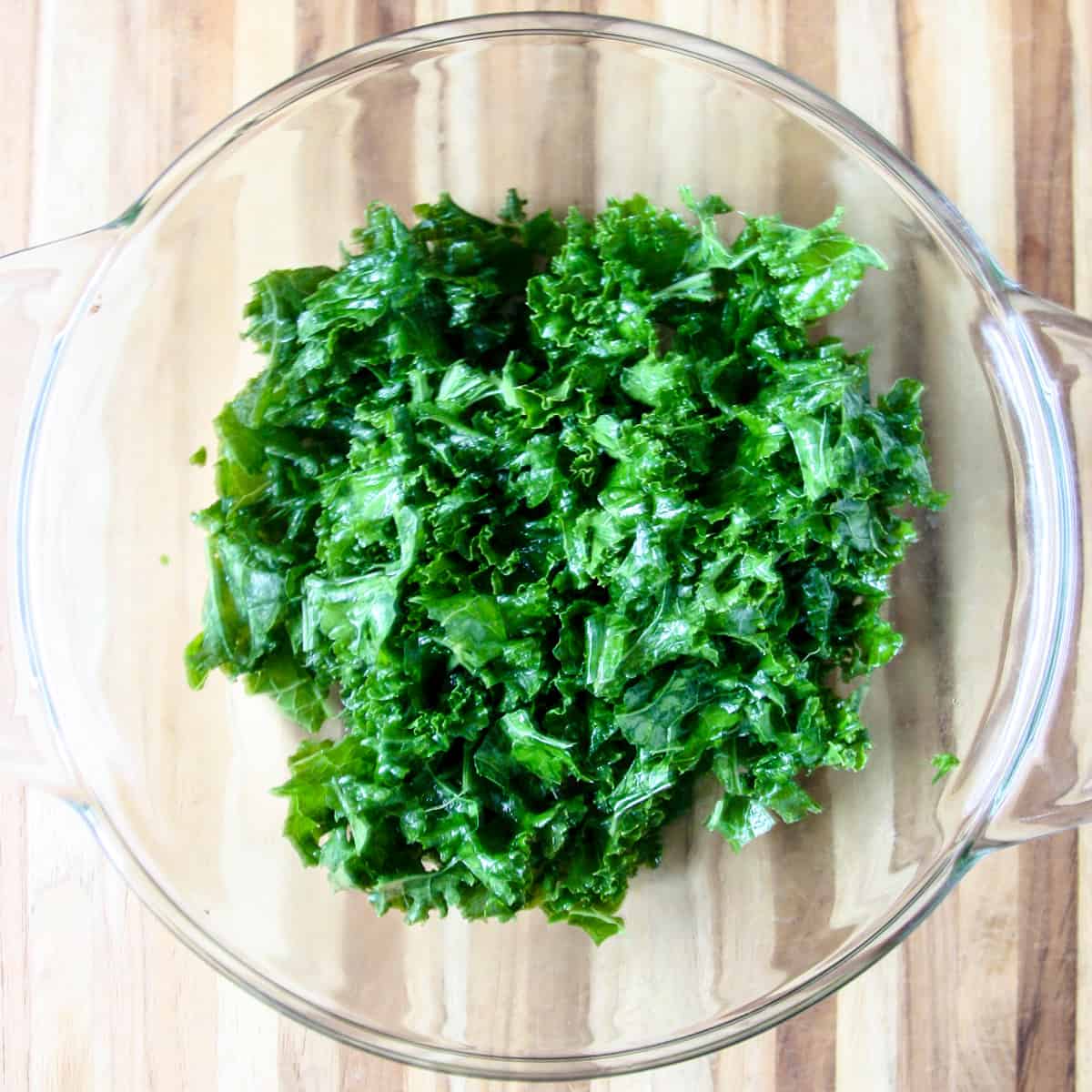 Kale leaves in a glass bowl after being massaged.