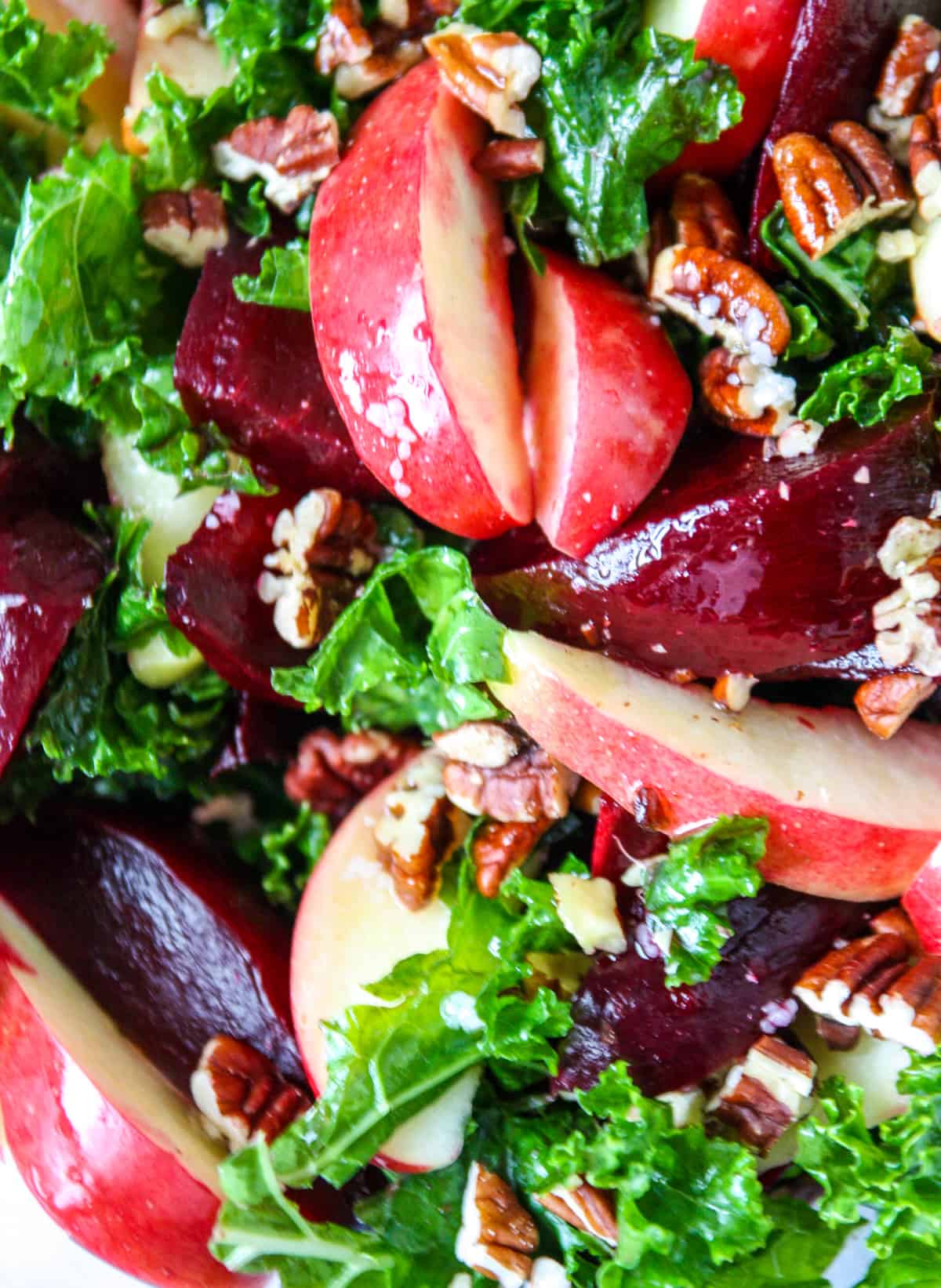 A close up shot of kale and beet salad with apples and walnuts.