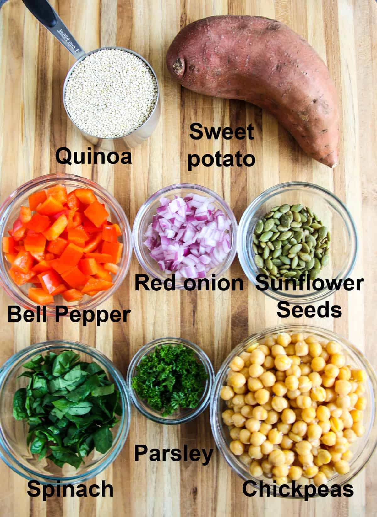 The salad ingredients, in glass bowls on a wooden board.