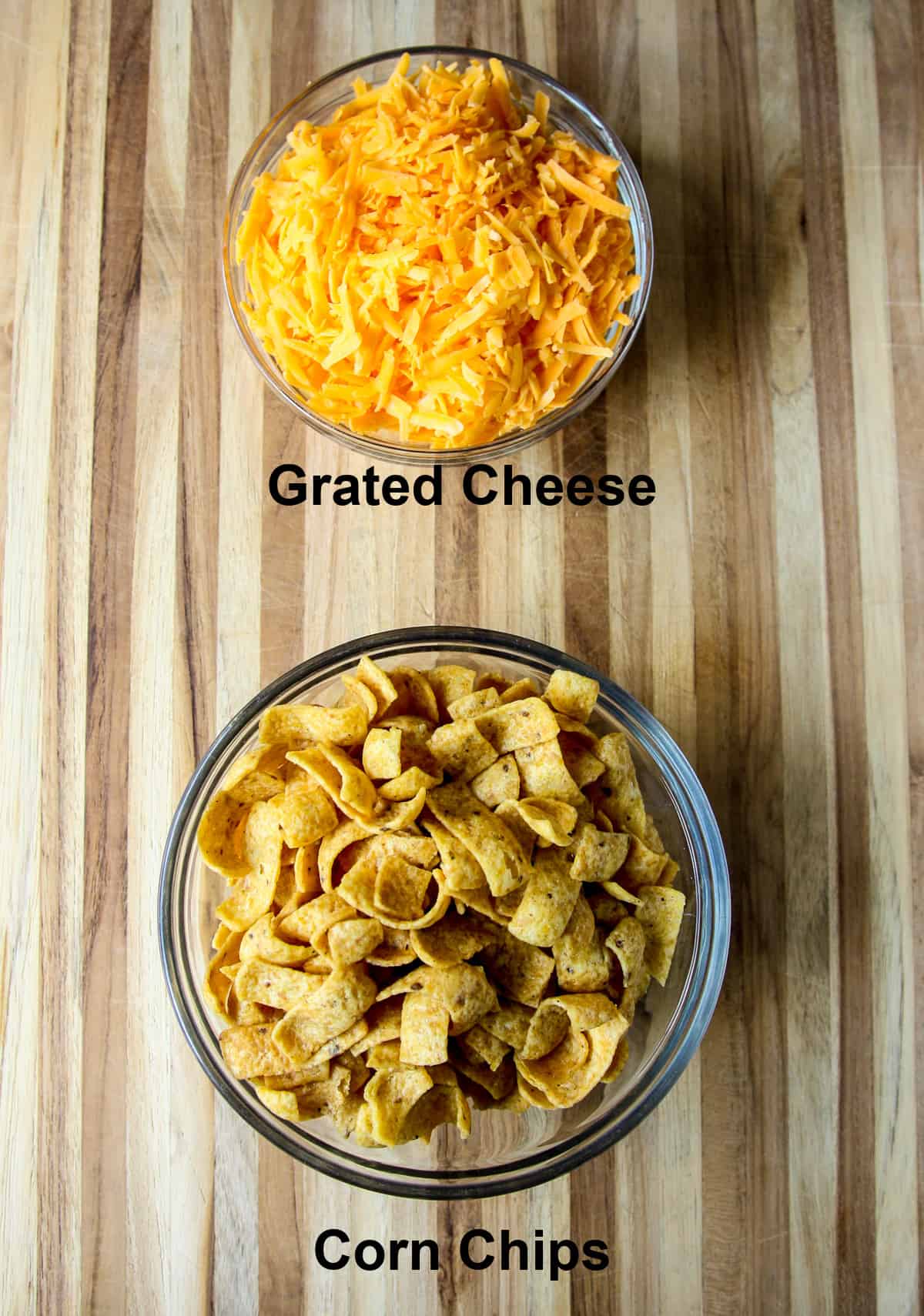 The casserole toppings; grated cheese and corn chips, in glass bowls.
