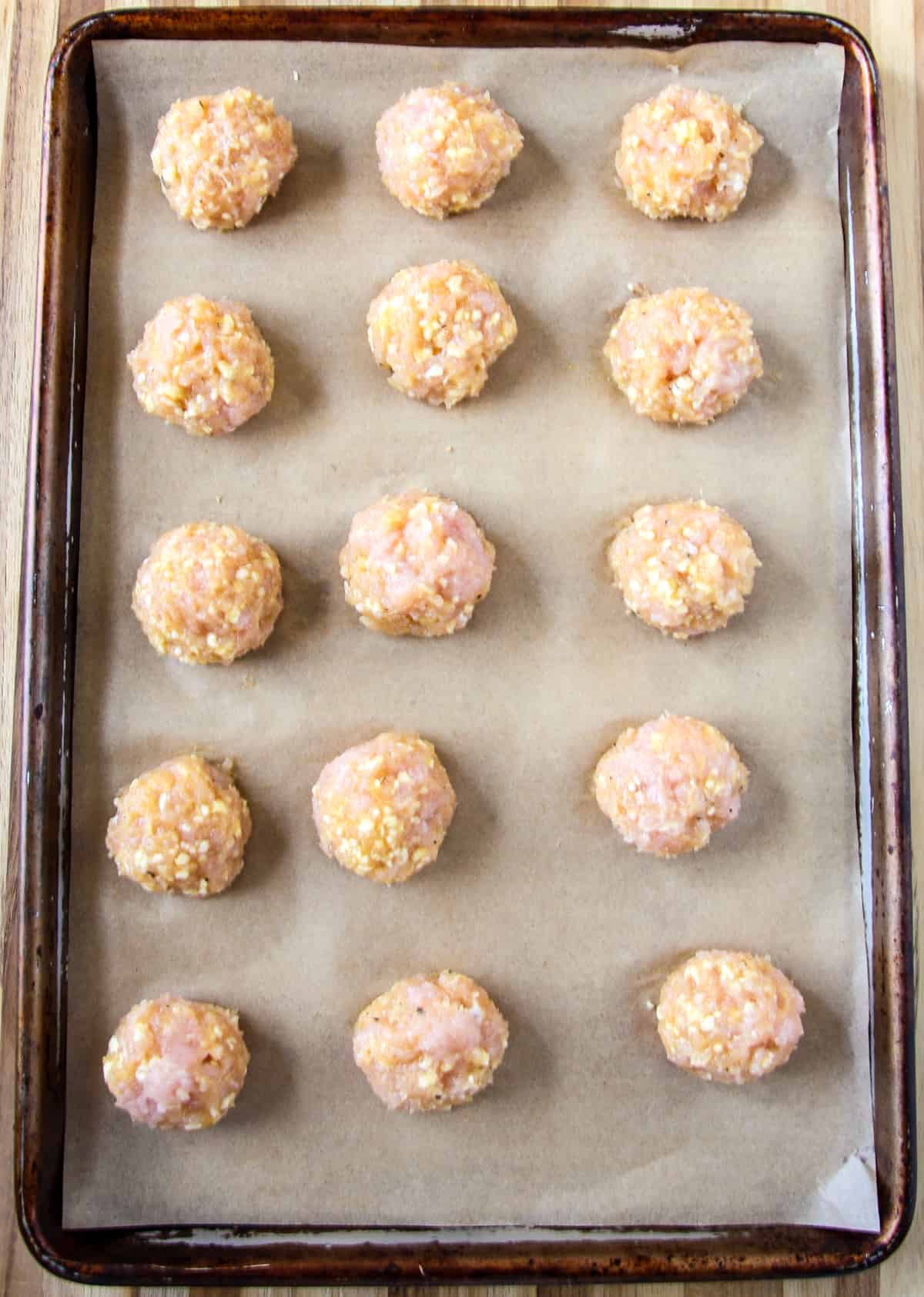 Raw meatballs on a baking sheet.
