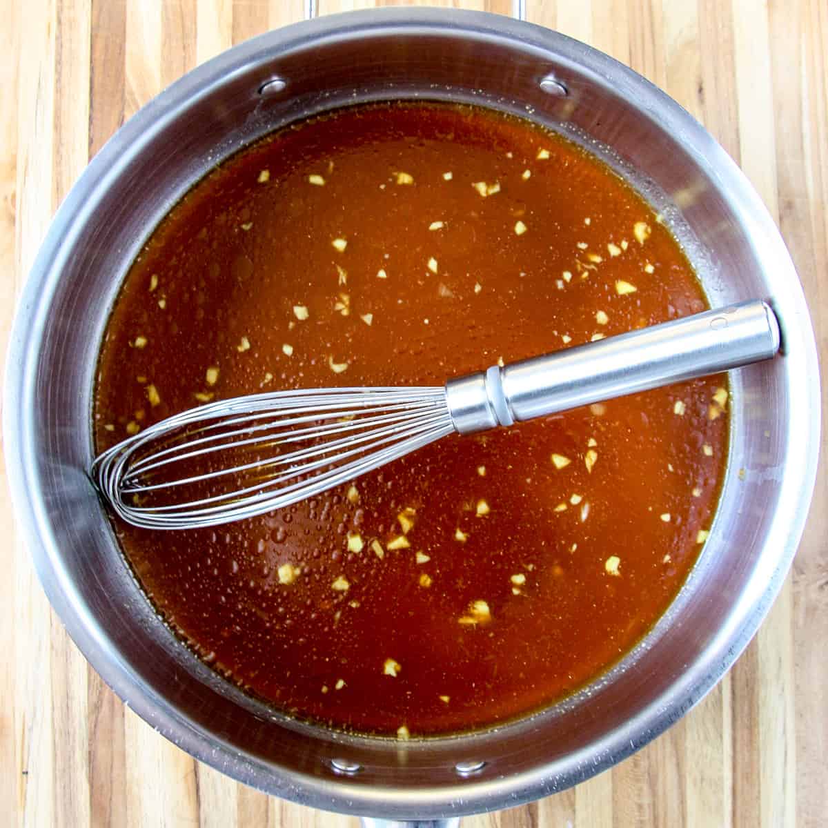 Sweet and sour sauce ingredients being whisked together in a sauce pan.