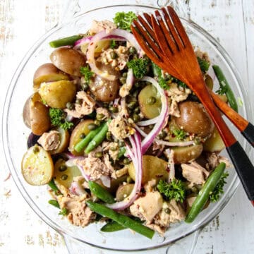Tuna Potato Salad in a glass bowl with two wooden forks.