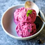 Three scoops of black currant ice cream in a light green dish.