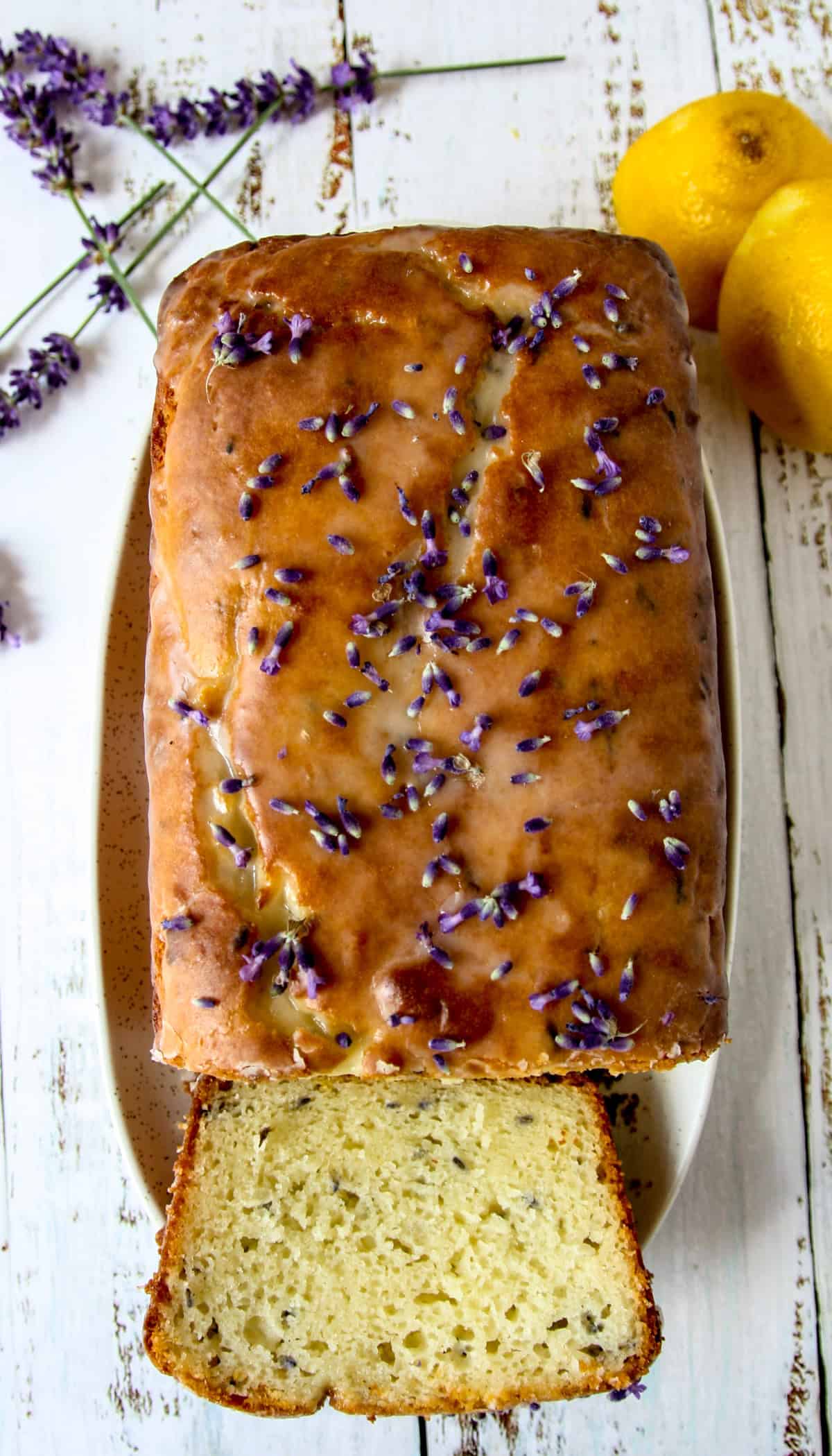 A loaf-shaped lemon lavender cake decorated with lavender flower buds.
