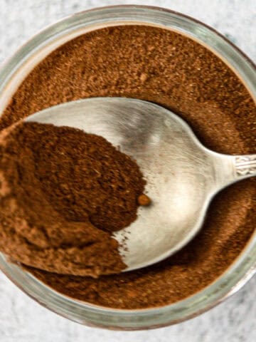 A jar of homemade pumpkin pie spice with a silver spoon.