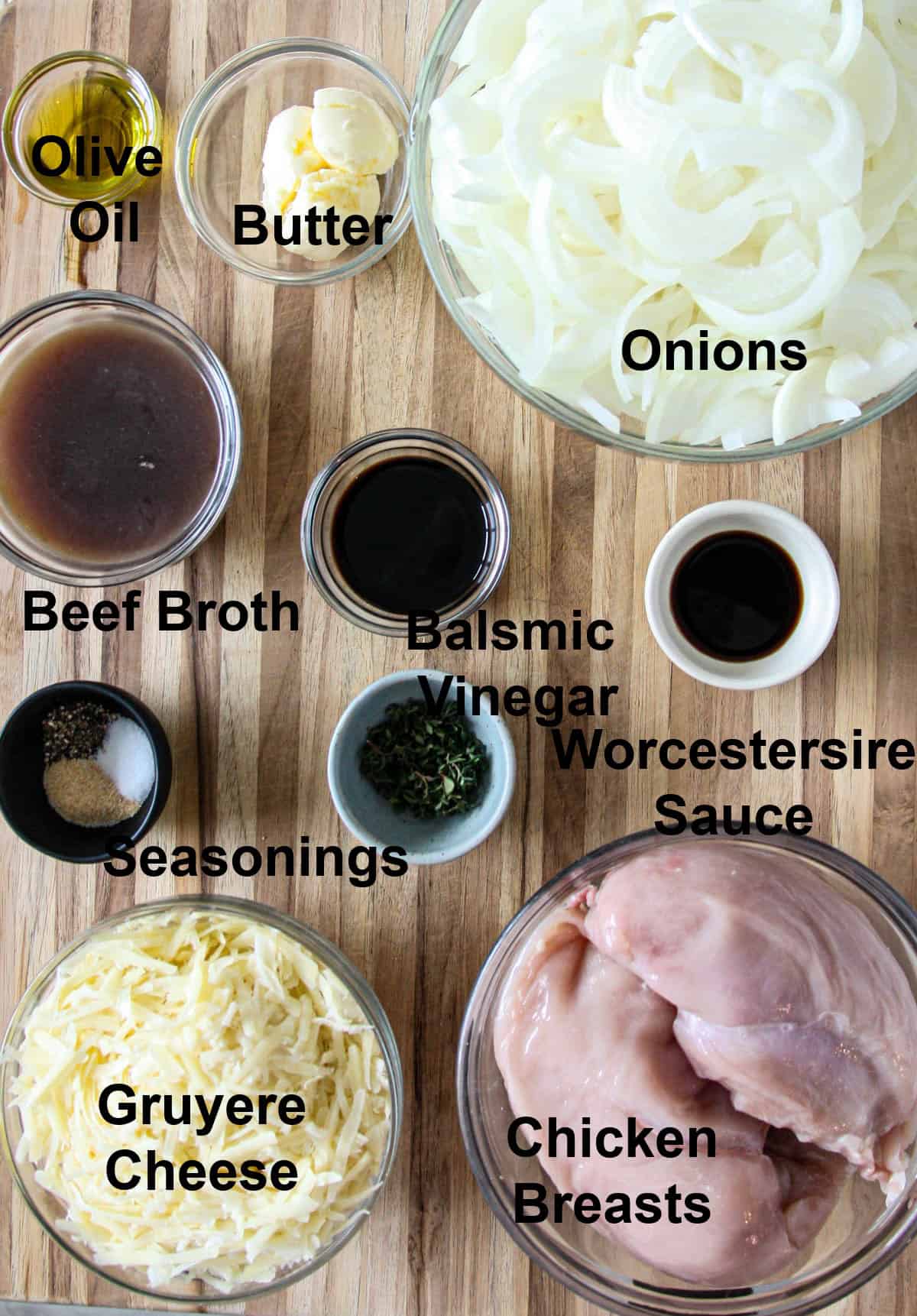 The ingredients for making French onion chicken in glass bowls on a wooden board.