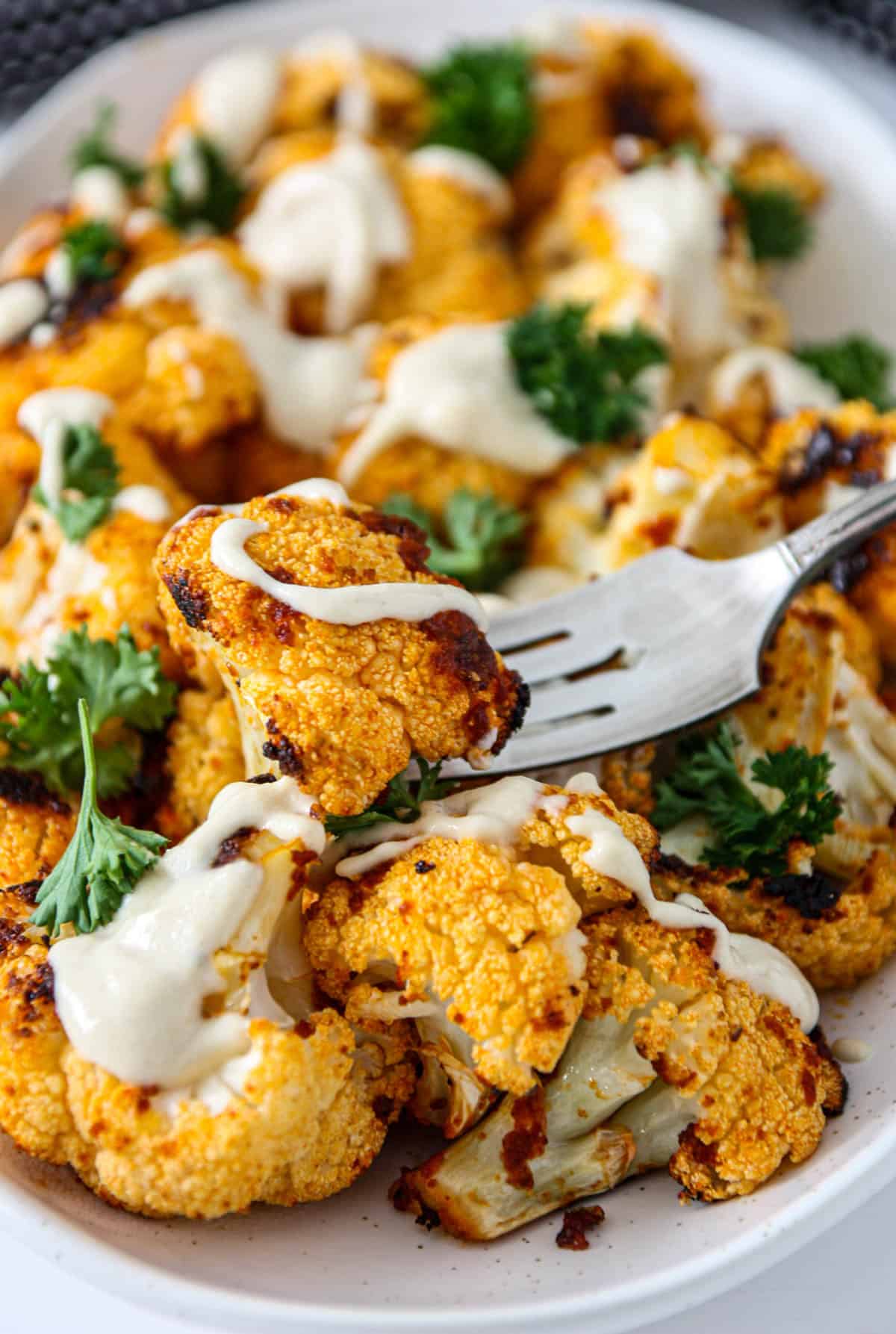 A platter of roasted cauliflower with tahini sauce.